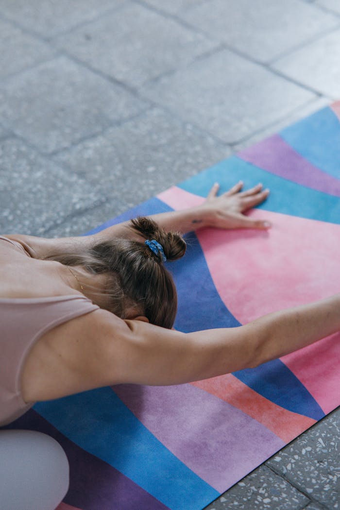 hero-img-01 A woman stretching in a yoga pose on a vibrant mat indoors, promoting calm and fitness.